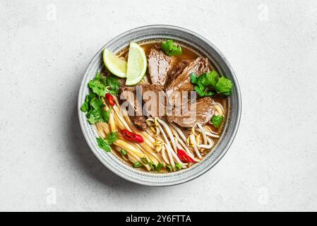 Pho Bo vietnamesische Suppe, Schüssel frische asiatische Suppe mit Reisnudeln, Rindfleisch, Kräutern, Sojasprossen und Chili auf weißem Hintergrund, Ansicht von oben. Asiatische Küche Stockfoto