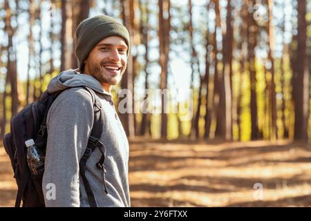 Lächelnder junger Backpacker beim Wandern mit Freunden im Wald Stockfoto