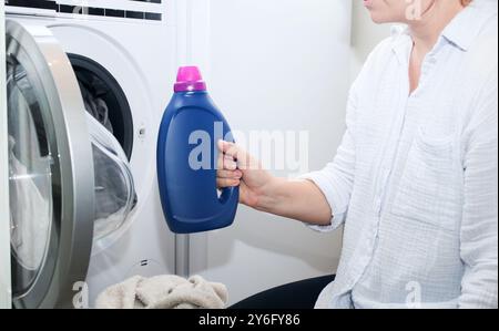 Nahaufnahme einer Frau, die eine blaue Flasche Waschmittel hält Stockfoto