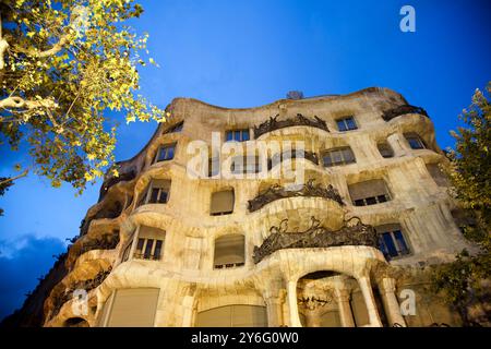 Erkunden Sie die atemberaubende Architektur von Gaudis La Casa Mila, wunderschön beleuchtet an einer Nacht in Barcelona, und heben Sie sein einzigartiges Design auf dem Paseo de hervor Stockfoto