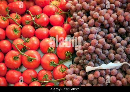 Farbenfrohe Tomaten und Traubengruppen werden im Mercat de la Boqueria ausgestellt, auf dem die lebhaften Produkte des Barcelonas Markts präsentiert werden. Stockfoto