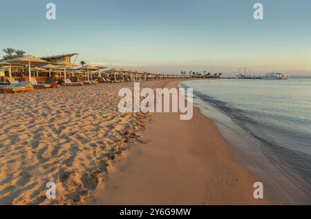Leerer Strand mit Liegestühlen und Sonnenschirmen am Morgen. Badeortküste ohne Menschen, Konzept des Zusammenbruchs der Tourismusbranche. Seeküste ist c Stockfoto