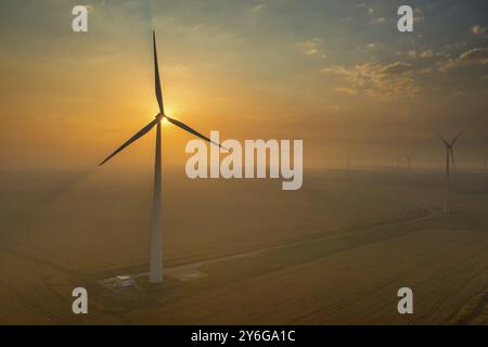 Wunderschöne Sonnenuntergangslandschaft mit Windmühlen oder Windturbinen auf dem abwechselnden Windpark zur Erzeugung von Elektrizität Stockfoto