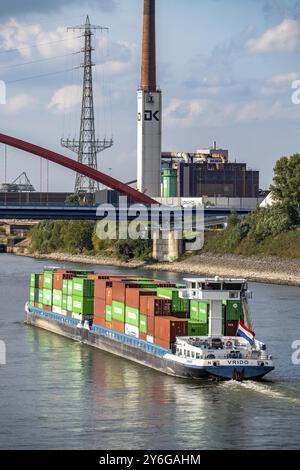 Das mit Containern beladene holländische Frachtschiff Vrido auf dem Rhein bei Duisburg, das hinter der sogenannten Solidaritätsbrücke über den Rhein hinabfährt; Stockfoto