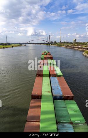 Das mit Containern beladene holländische Frachtschiff Vrido auf dem Rhein bei Duisburg, das hinter der sogenannten Solidaritätsbrücke über den Rhein hinabfährt; Stockfoto