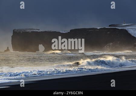 Schneebedeckter Strand, Wellen, Wind, dunkle Wolken, Winter, leichte Stimmung, Felsen, Dyrholaey, Vik, Island, Europa Stockfoto