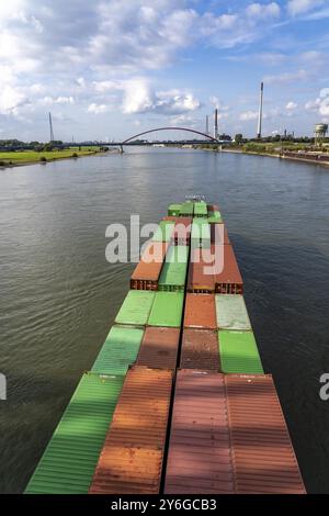 Das mit Containern beladene holländische Frachtschiff Vrido auf dem Rhein bei Duisburg, das hinter der sogenannten Solidaritätsbrücke über den Rhein hinabfährt; Stockfoto
