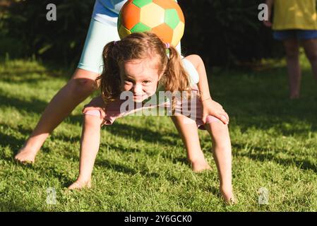 Kinder spielen Fußball auf dem Garten. Lustiges Mädchen mit Football Stockfoto