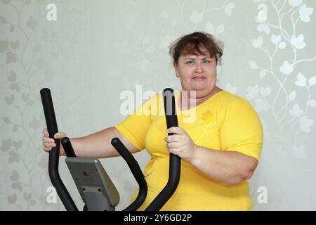 Übergewichtige Frau, die auf Trainerellipsoid trainiert Stockfoto