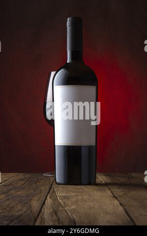 Essen, Werbeshot aus Glas und Flasche Rotwein mit leerem Etikett rostig brauner Hintergrund. Modell, Frontalansicht Stockfoto