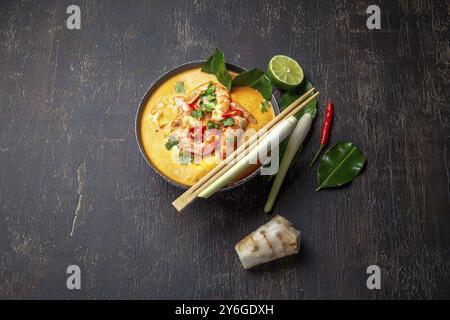 Essen, Essen, Garnelen Tom Yam Kung in grauer Schüssel mit thailändischen Gewürzen auf autentischem Tablett von oben, hölzerner Hintergrund Stockfoto