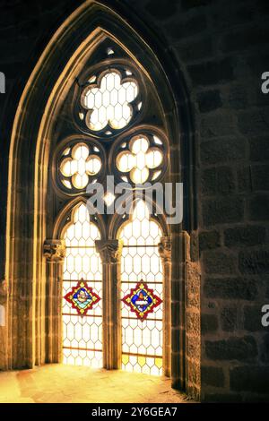 Sonnenlicht scheint durch Buntglas aus gotischen Fenstern einer Kirche Stockfoto