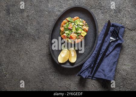 Essen, Essen, PERUANISCHES NIKKEI ESSEN. Lachsavocado Ceviche auf schwarzer Platte, schwarzer Hintergrund von oben Stockfoto