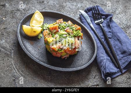 Essen, Essen, PERUANISCHES NIKKEI ESSEN. Lachsavocado Ceviche auf schwarzer Platte, schwarzer Hintergrund von oben Stockfoto