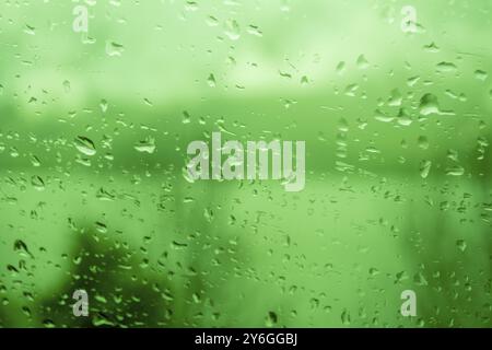 Regentropfen an einem Fenster, die das graue und regnerische Wetter während des Tages veranschaulichen. Schwarzweiß-Graustufen Stockfoto