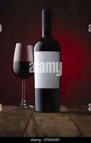 Essen, Werbeshot aus Glas und Flasche Rotwein mit leerem Etikett rostig brauner Hintergrund. Modell, Frontalansicht Stockfoto