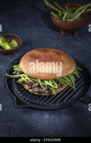 Essen, Essen, chilenischer lateinamerikanischer Sandwich-Burger Chacarero mit erstklassigen Rindfleischscheiben und grüner Bohne auf schwarzem Hintergrund Stockfoto