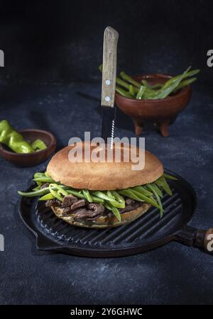 Essen, Essen, chilenischer lateinamerikanischer Sandwich-Burger Chacarero mit erstklassigen Rindfleischscheiben und grüner Bohne auf schwarzem Hintergrund Stockfoto