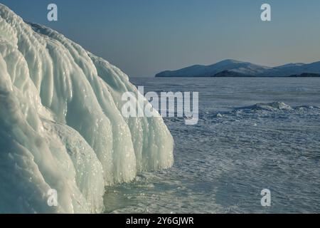 Eis und Eiszapfen auf den Felsen am Lake Baikal bei frostigem Sonnenuntergang im Winter Stockfoto