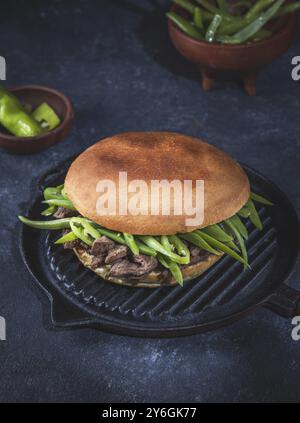 Essen, Essen, chilenischer lateinamerikanischer Sandwich-Burger Chacarero mit erstklassigen Rindfleischscheiben und grüner Bohne auf schwarzem Hintergrund Stockfoto