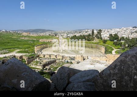 Griechisch-römische Ruinen von Gerasa und die moderne Stadt Jerash im Hintergrund. Oval Forum, Säulenstraße und Cardo Maximus in freier Sicht Stockfoto