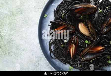 Essen, Schwarze Spaghetti, neri Nudeln, mit Muscheln, Blick von oben, auf grauem Hintergrund, hausgemacht, keine Leute Stockfoto