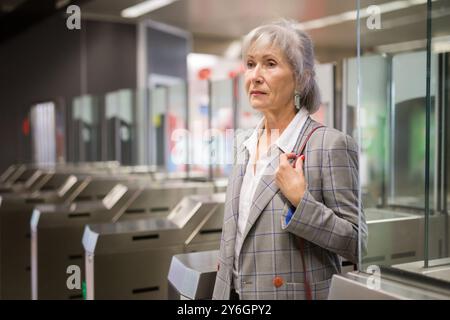 Reife Dame geht durch die Schranken in der U-Bahn-Station Stockfoto