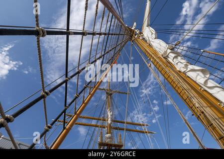 Flacher Blick auf Holzmasten und Takelage unter blauem Himmel mit Wolken Stockfoto