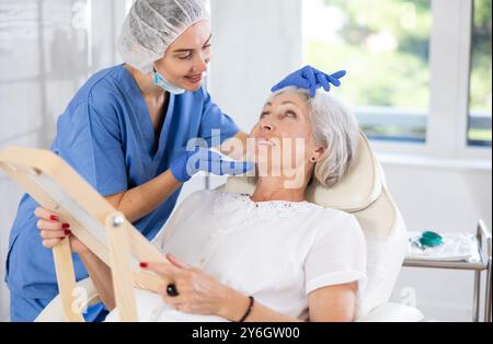 Der ältere Patient sieht in der Klinik in den Spiegel. Stockfoto