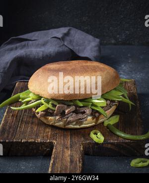 Essen, Essen, chilenischer lateinamerikanischer Sandwich-Burger Chacarero mit erstklassigen Rindfleischscheiben und grüner Bohne auf schwarzem Hintergrund Stockfoto