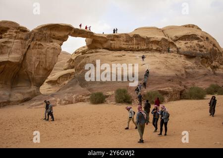Wadi Rum, Jordanien, März 2020: Menschen, Touristen, Kletterei auf der um Frouth Natural Rock Bridge, Asien Stockfoto