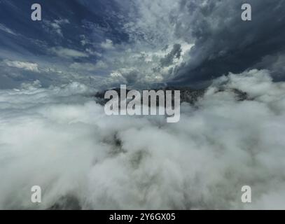 Luftaufnahme der Berge in dramatischen Sturmwolken. Wunderschöne Landschaft mit Berggipfel im Nebel Stockfoto