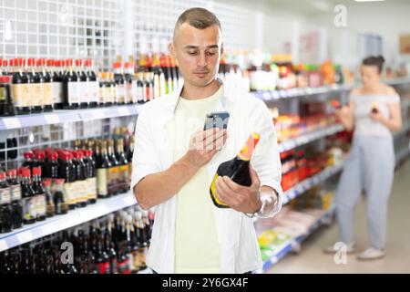 Mann, der nach Sojasauce sucht, auf dem Foto im Internet Stockfoto