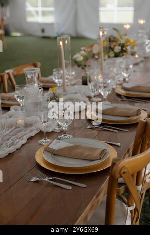 Ein wunderschön gedeckter Esstisch mit elegantem Geschirr, Kerzen und Blumendekoration, bereit für eine formelle Veranstaltung oder einen Hochzeitsempfang. Stockfoto