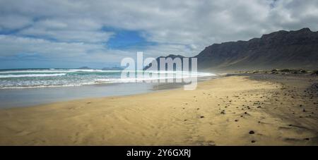 Panoramablick auf Famara Beach auf der Kanarischen Insel Lanzarote, mit Windsurfen in der Ferne Stockfoto