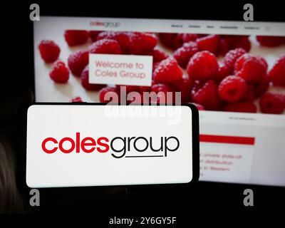 In dieser Abbildung hält eine Person ein Smartphone mit dem Logo des australischen Einzelhandelsunternehmens Coles Group Limited vor der Website. Stockfoto