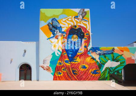 Ein wunderschönes Wandgemälde einer Dame mit einem Kopftuch von Mohawudu (Ghana) im Mina District in Doha, Katar Stockfoto