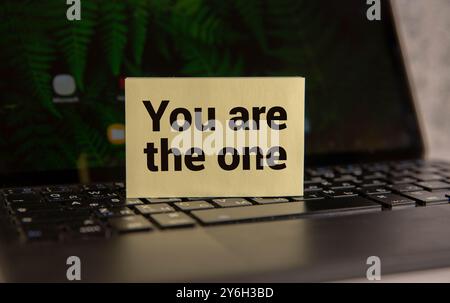 Holzklatschnadel mit weißem Blatt Papier. Text „Du bist nicht allein“. Schöner Holzhintergrund. Geschäftskonzept, Kopierbereich. Stockfoto
