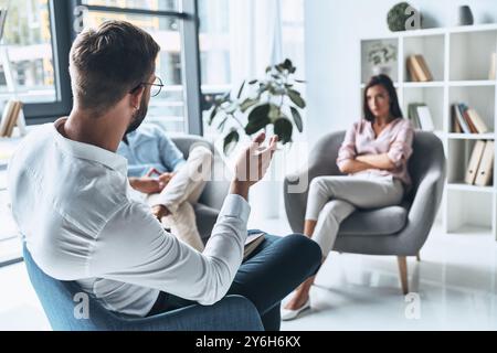 Er weiß, wie man Paaren hilft. Junge verheiratete Paare im Gespräch während der Therapiesitzung mit Psychologen Stockfoto