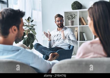 Helfende Paare. Junge verheiratete Paare, die auf Psychologen hören, während sie in der Therapiesitzung sitzen Stockfoto