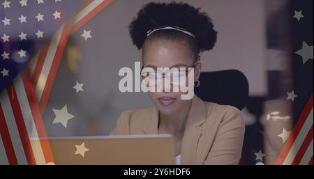 Bild der Flagge der usa über glücklicher afroamerikanischer Geschäftsfrau mit Laptop Stockfoto