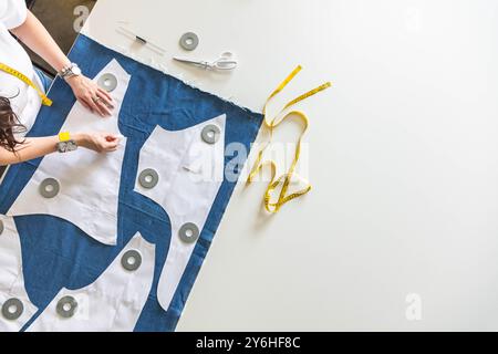 Eine Schneiderin legt Musterdetails auf Denim und schneidet Kleidung. Draufsicht. Stockfoto