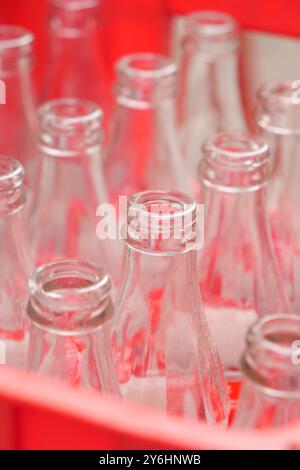 Leere Glasflaschen in einem leuchtend roten Korb zur Aufbewahrung und Organisation Stockfoto
