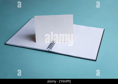 Leere weiße Karte auf dem Notizblock und blaue Tischplatte. Stockfoto