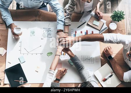 Erfolgreiches Team. Nahaufnahme von oben: Geschäftskollegen, die Hände übereinander halten, als Symbol der Einheit, während sie im kreativen Leben sitzen Stockfoto