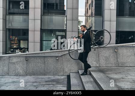 Vermeiden von Verkehr. Ein junger Mann in voller Länge, der sein Fahrrad trägt, während er draußen läuft Stockfoto