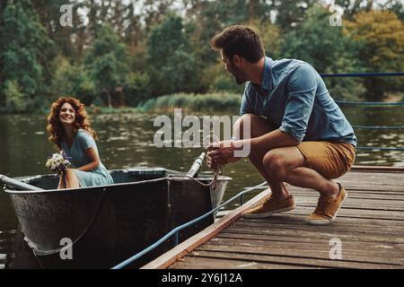 Echte Liebe. Glückliches junges Paar, das sich bereit macht, ein Boot zu rudern, während es ihr Date im Freien genießt Stockfoto