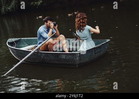 Schöne Aufnahme. Junger Mann, der seine schöne Freundin fotografiert, während er ein romantisches Date auf dem See genießt Stockfoto