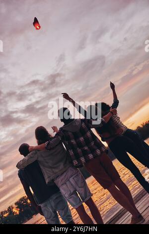 Hoch am Himmel. Rückansicht junger Menschen, die sich umarmen und Gesten beim Blick auf die schwimmende Himmelslaterne Stockfoto