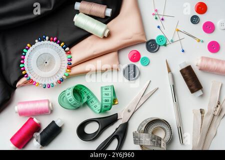 Bastelbedarf für Nähprojekte, die auf einem Tisch mit Stoff, Fäden und Werkzeugen dargestellt werden Stockfoto